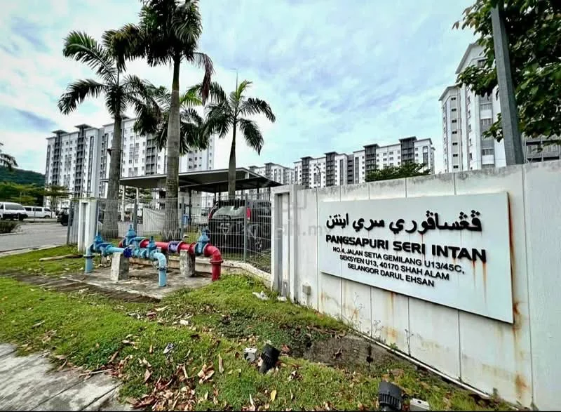 Exterior type: low-rise apartment block; features: white painted facade, security gate at entrance, landscaped garden, manicured lawn, visible water pipes, surrounded by greenery, multiple-storey building, parking area; style: modern.