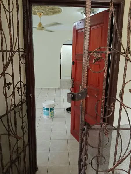 Room features: tiled flooring, white walls, wooden door with red finish, metal security gate, ceiling fan, bucket on floor.