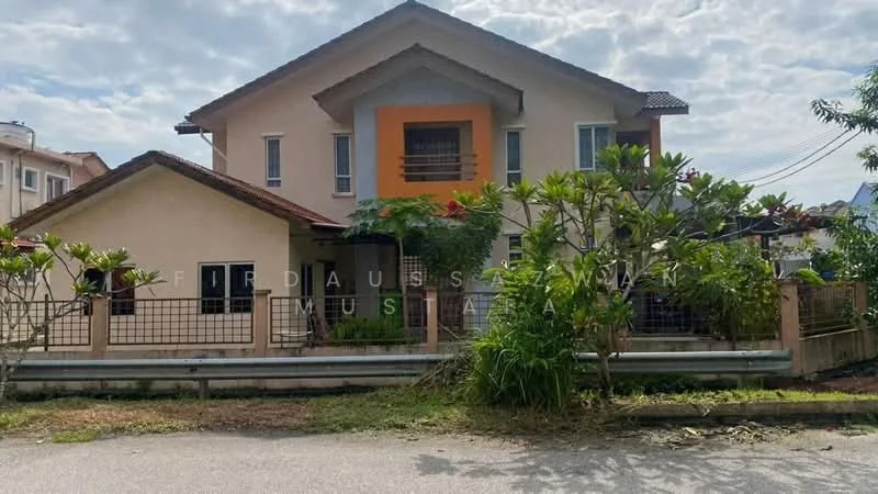 Exterior type: detached bungalow; features: two-storey building, cream painted facade, brown tiled roof, front porch with railing, landscaped garden with shrubs, paved driveway, fenced perimeter, balcony on upper floor, multiple windows, visible electrical wiring, surrounded by greenery; style: modern.
