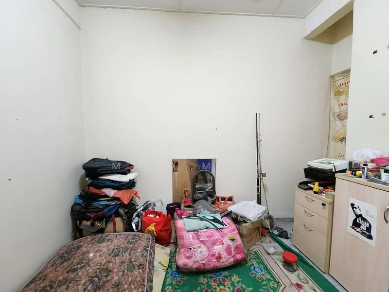 Room features: cream painted walls, grey carpet flooring, single bed with mattress, stack of clothing on the floor, wooden cabinet, plastic storage containers, decorative wall poster, area rug with floral pattern.