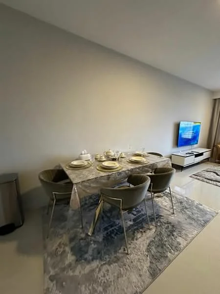 Dining features: 6-seater dining table with marble top, upholstered dining chairs in grey, decorative area rug with abstract pattern, wall-mounted TV, TV console in white, neutral painted walls, large windows with sheer curtains, recessed downlights; style: modern.