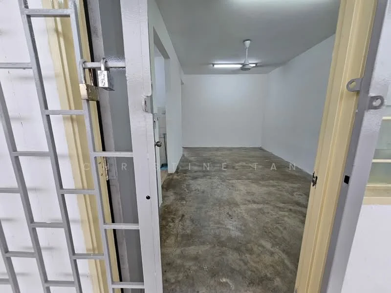 Room features: concrete flooring, white painted walls, ceiling fan, door with security grille, light fixture on ceiling, open layout, no visible furniture, neutral color scheme; style: minimalist.