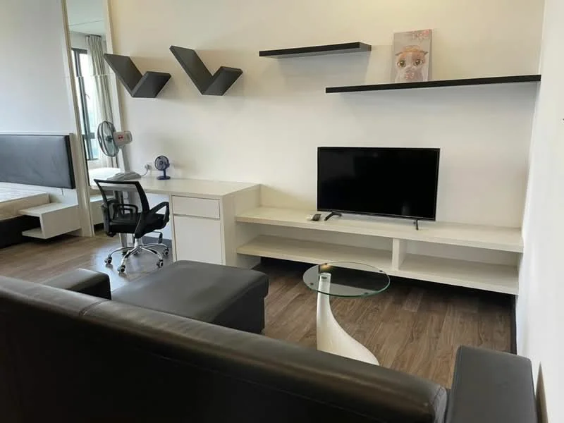 Living features: black leather sofa, glass coffee table, white TV console, wall-mounted shelves, flat-screen TV, desk with chair, wooden flooring, fan, decorative artwork, neutral painted walls; style: modern.