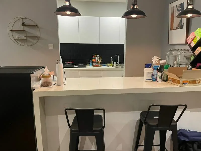 Kitchen features: white cabinetry, black tile backsplash, stainless-steel sink, chrome pull-down faucet, countertop with bar seating, black bar stools, built-in stove, kitchen appliances visible, open shelving, wall-mounted light fixtures; style: modern.