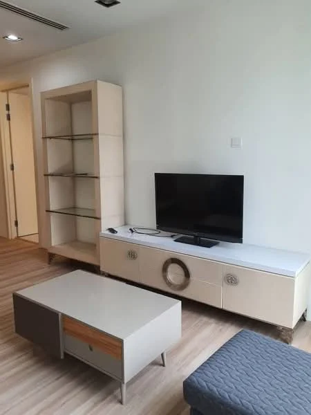 Living features: light wood flooring, white painted walls, built-in shelving unit, TV console with decorative circular handle, flat-screen TV, coffee table with drawer, upholstered ottoman, recessed ceiling lights; style: modern.
