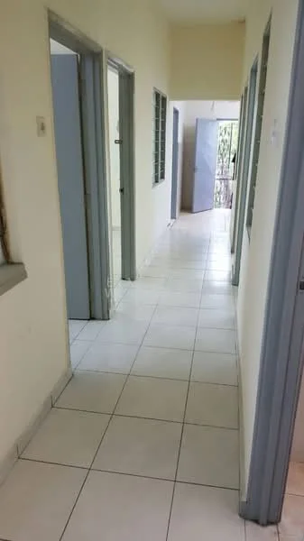 Hallway features: white painted walls, ceramic tile flooring, grey doors, windows with metal grilles, light switch, door frames, natural light from windows, neutral color scheme.