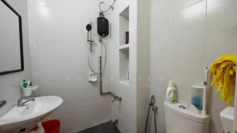 Bathroom features: white tiled walls, grey tiled flooring, single-sink vanity with chrome faucet, mirror above sink, shower area with wall-mounted shower head, water heater unit, built-in shelving unit, toilet, cleaning supplies on shelf, yellow towel hanging; style: modern.