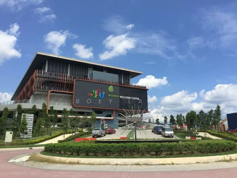 Exterior type: welcome center; features: modern facade with large signage, multi-storey building, landscaped entrance with greenery, paved driveway, visible parking area, decorative sculpture in front, large windows, overhanging roof, surrounded by manicured lawns; style: modern.