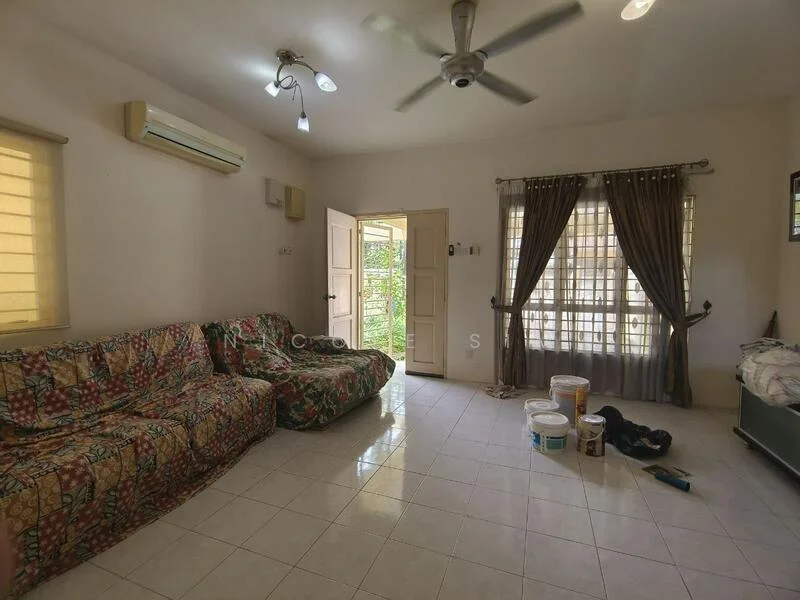 Living features: 2-seater fabric sofa with floral pattern, ceiling fan, wall-mounted air conditioning unit, white painted walls, tiled flooring, large windows with sheer curtains, double-door entrance, decorative curtains, paint buckets on the floor, shoe rack, greenery visible through the door; view: garden.