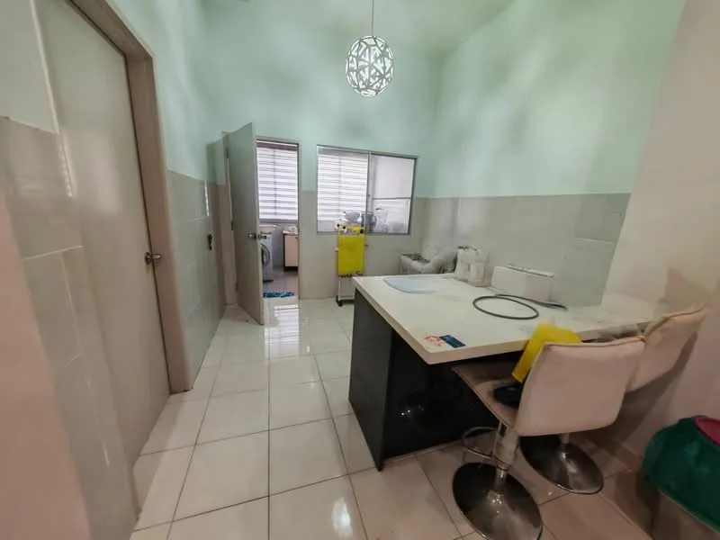 Kitchen features: light green painted walls, white tiled flooring, pendant light fixture, kitchen island with black countertop, two white bar stools, window with blinds, door leading to another room, sink, appliances visible in the background; style: modern.