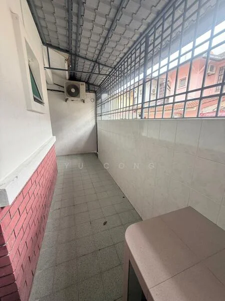 Room features: grey tiled flooring, white tiled walls, red brick accent wall, metal grating ceiling, wall-mounted air conditioning unit, window with metal bars, open space layout, natural light from window.