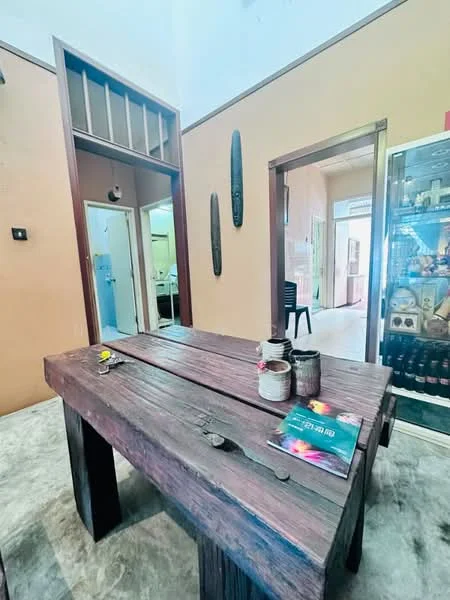 Room features: wooden dining table, two chairs, decorative items on table, painted walls in beige, grey flooring, wall-mounted artwork, doorway leading to another room, glass display cabinet, light source from ceiling, open space layout; style: traditional.