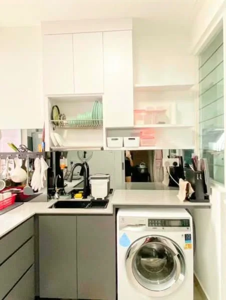 Kitchen features: grey cabinetry, white countertop, single-bowl stainless-steel sink, chrome pull-down faucet, built-in washing machine, open shelving, dish rack, kitchen utensils, glassware, wall-mounted mirror; style: modern.