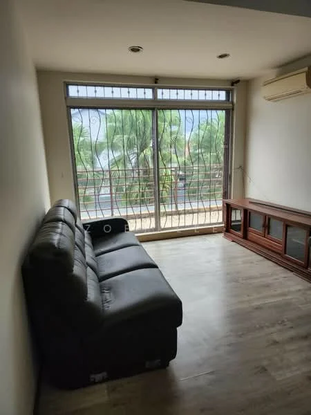 Living features: 3-seater leather sofa in dark grey, wooden TV console, large sliding glass door, floor-to-ceiling windows, laminate flooring, air conditioning unit, decorative window grills, natural light from windows, view of greenery outside; style: modern; view: garden.