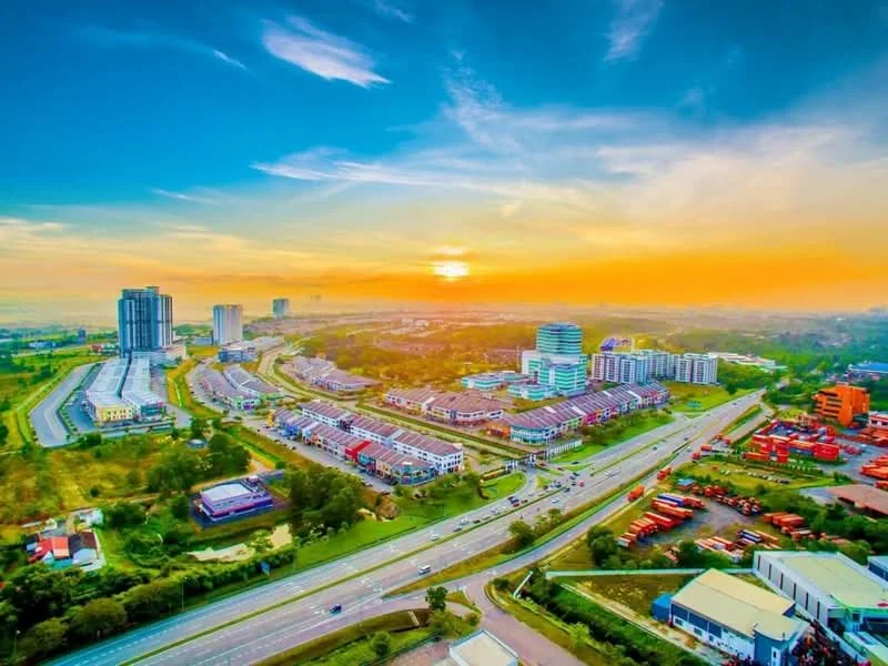 Exterior type: high-rise condominium; features: city skyline, sunset view, surrounded by greenery, main road in foreground, multiple buildings, urban landscape; style: modern.