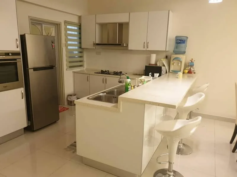 Kitchen features: white cabinetry, stainless-steel fridge, built-in oven, 4-burner gas hob, single-bowl stainless-steel sink, chrome pull-down faucet, white quartz countertop, bar seating with white stools, tile flooring, window with horizontal blinds, water dispenser, kitchen exhaust hood; style: modern.