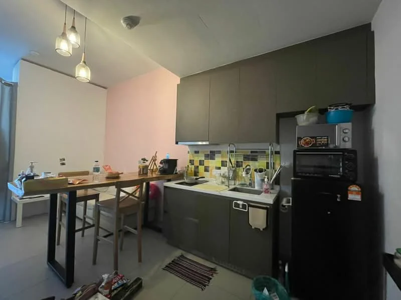 Kitchen features: grey cabinetry, white countertop, stainless-steel sink, chrome pull-down faucet, built-in microwave, freestanding fridge, 4-burner gas hob, tile backsplash with yellow and green accents, pendant lighting, dining table with chairs, open shelving, floor tiles, wall-mounted storage, kitchen utensils visible; style: modern.