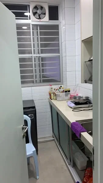 Kitchen features: white tiled walls, light grey flooring, single-bowl stainless-steel sink, chrome pull-down faucet, flat-panel white cabinets, countertop with storage underneath, washing machine, window with metal grille, exhaust fan, kitchen utensils on countertop, bottle storage on countertop, purple cloth hanging, open shelving; style: modern.