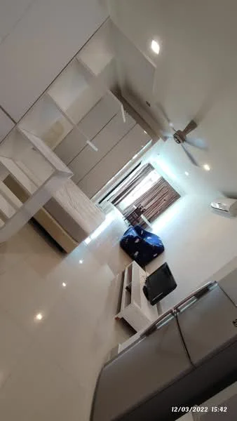 Living features: white painted walls, glossy tile flooring, 5-blade ceiling fan with light, floor-to-ceiling windows, sheer curtains, sofa in blue fabric, TV console, wall-mounted TV, decorative wall shelving, air conditioning unit, coffee table, bed with mattress, built-in wardrobe; style: modern.