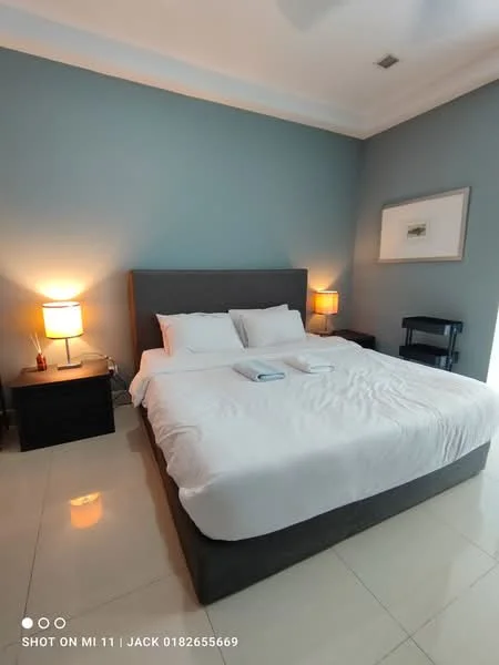 Bedroom features: king-size bed with white bedding, upholstered headboard, 2 bedside lamps with warm light, dark wood bedside tables, light blue painted walls, polished tile flooring, ceiling fan, framed artwork on wall, window with natural light; style: modern.