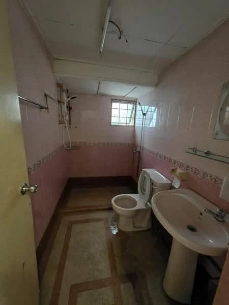 Bathroom features: pink tiled walls, white ceramic toilet, white sink with pedestal, shower with wall-mounted faucet, window for natural light, tile flooring with decorative border, towel rack, mirror above sink.