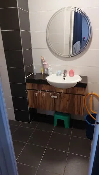 Bathroom features: single-sink vanity with wood cabinet, black countertop, round mirror, white ceramic sink, chrome basin mixer faucet, tile flooring in dark grey, white tiled walls, black accent wall, toilet, green stool, toiletries on countertop; style: modern.