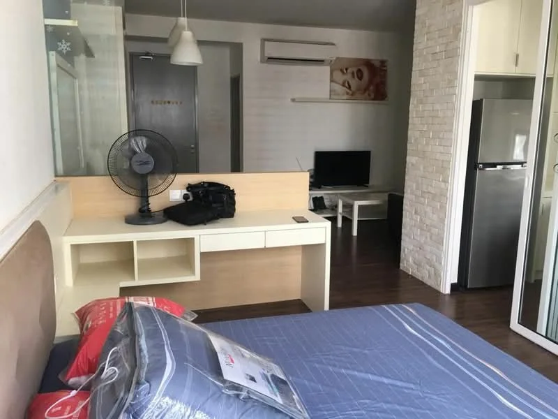 Bedroom features: queen-size bed, upholstered headboard, bedside table with drawer, desk with storage, wall-mounted TV, floor fan, air conditioning unit, wooden flooring, decorative wall with stone cladding, window with sheer curtains; style: modern. Room features: refrigerator, coffee table.