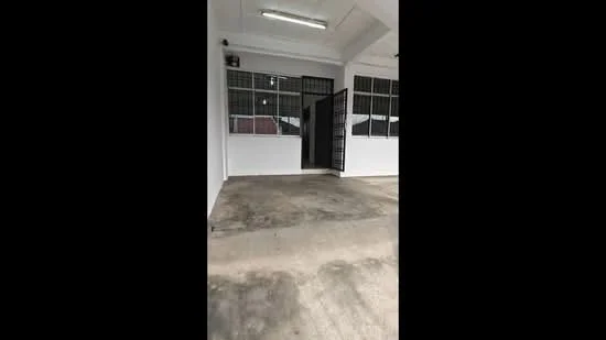Room features: concrete flooring, white painted walls, large windows with metal grilles, double door entry, fluorescent ceiling lights.