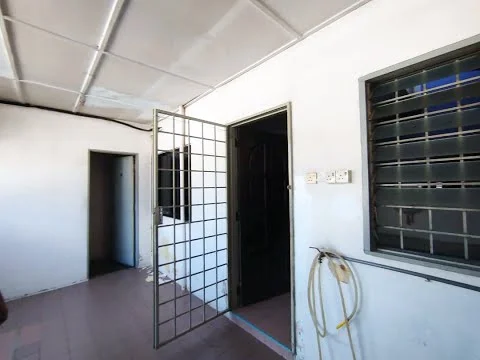 Room features: white painted walls, metal security grille door, window with metal bars, plain ceiling, tile flooring, visible electrical outlets, hose coiled on the wall.