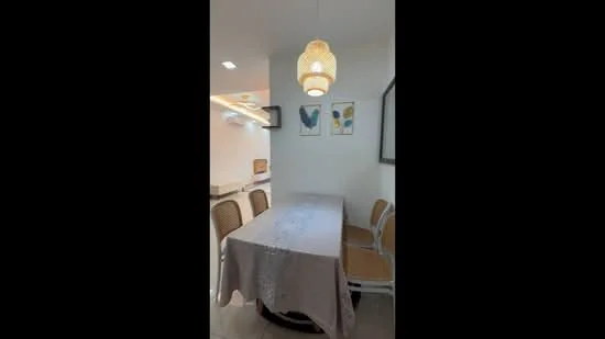 Dining features: round dining table, 4 dining chairs, white tablecloth, pendant light fixture, framed artwork on walls, white painted walls, tile flooring, recessed lighting; style: modern.