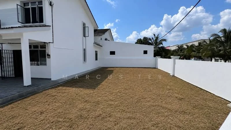 Exterior type: detached bungalow; features: white painted facade, flat roof, manicured lawn, surrounded by white boundary wall, paved walkway, tropical landscaping, clear blue sky, sunny weather; style: modern.