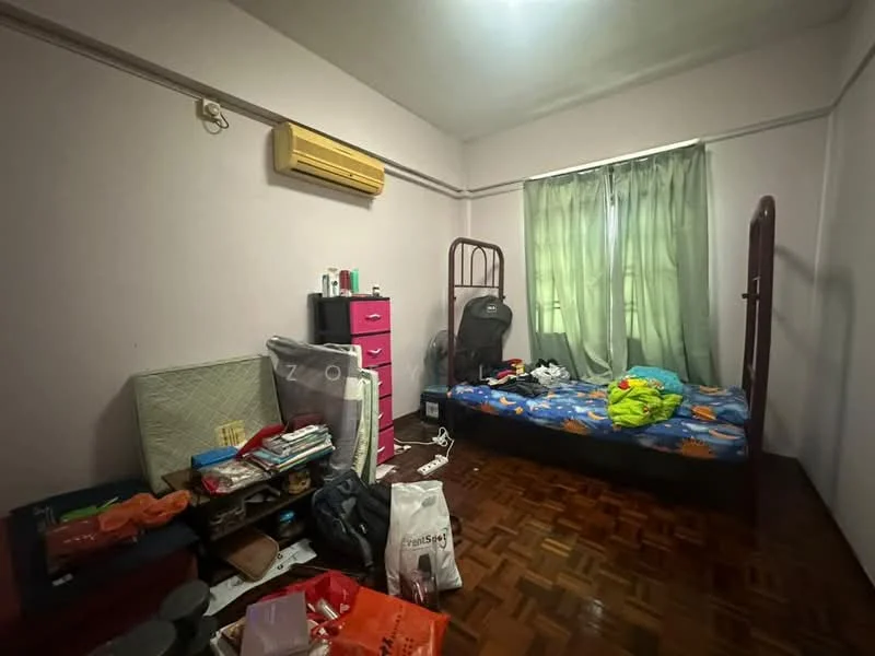 Bedroom features: wooden flooring, light purple painted walls, green curtains, single bed with colorful bedding, wall-mounted air conditioning unit, pink dresser, cluttered with various items, window with natural light.