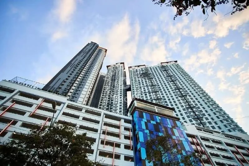 Exterior type: high-rise condominium; features: glass curtain wall, exposed concrete facade, multi-storey car park, projecting balconies, feature lighting at night, surrounded by mature greenery; style: modern.