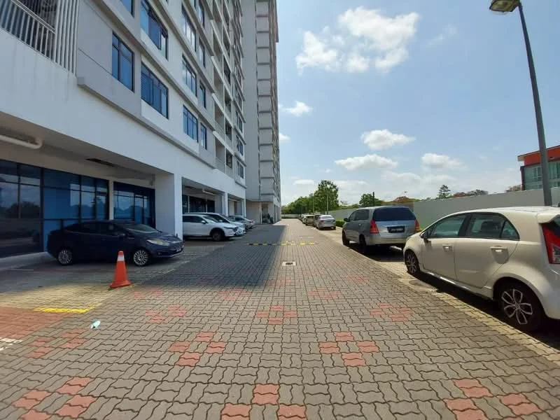 Exterior type: mid-rise condominium; features: paved parking lot, multiple parked cars, landscaped area with greenery, sidewalk, building facade with large windows, light fixtures along the pathway; style: modern.
