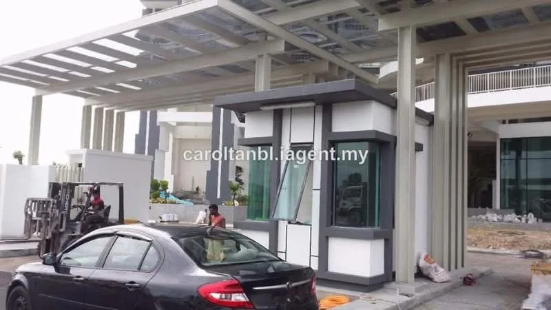 Exterior type: main entrance gate; features: modern facade with glass and concrete, security guardhouse, covered entrance with roof overhang, large glass windows, grey and white color scheme, surrounded by landscaping, parking area visible, vehicle access point; style: modern.