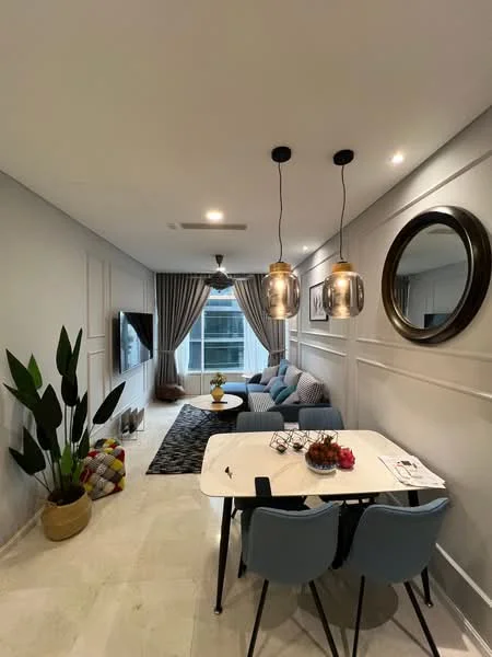 Living features: light grey painted walls, white ceiling with recessed lighting, 3-seater fabric sofa in blue, 2 accent cushions in geometric patterns, coffee table with white top, black area rug, wall-mounted TV, decorative mirror, pendant lighting fixtures, large window with sheer curtains, indoor plant in a pot, dining table with 4 blue chairs; style: modern; view: city.