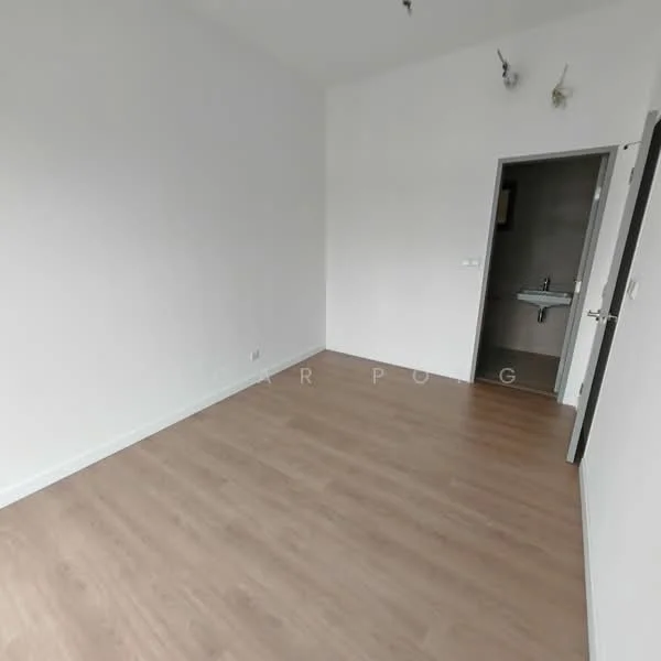 Room features: light wood laminate flooring, white painted walls, ceiling light fixture, doorway leading to bathroom, doorway leading to hallway, no visible windows.