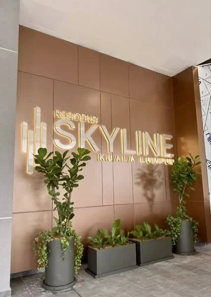 Exterior features: metal facade with bronze finish, illuminated signage, planters with greenery, paved flooring, decorative wall design; style: modern.