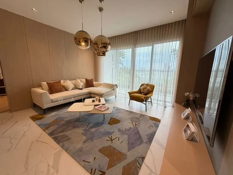 Living features: L-shape sectional sofa in cream, decorative cushions in various patterns, round coffee table in white, area rug with abstract pattern, floor-to-ceiling windows with sheer curtains, hanging pendant lights in gold, accent chair in mustard yellow, wall-mounted TV, light marble flooring, wood panel accent wall; style: modern; view: garden.