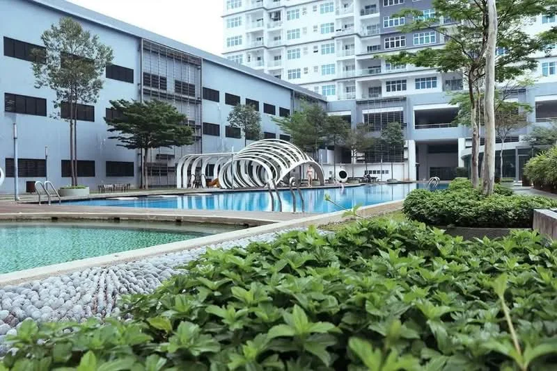 Exterior type: high-rise condominium; features: infinity pool, swimming pool deck with loungers, landscaped garden with shrubs, manicured lawn, modern architectural design, water feature with pebbles, surrounding greenery, multiple storeys visible, balconies on upper floors; style: modern.