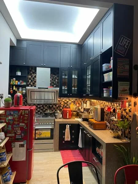 Kitchen features: black cabinetry, stainless-steel range hood, built-in oven, 4-burner gas hob, granite countertop, tile backsplash with mosaic pattern, single-bowl stainless-steel sink, chrome pull-down faucet, refrigerator in red, open shelving, under-cabinet lighting, wooden cutting board, kitchen towels, decorative plants, red area rug; style: modern.