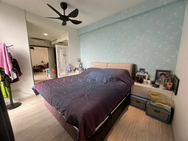 Bedroom features: king-size bed with upholstered headboard, bedding in dark purple, light blue accent wall with floral pattern, wooden flooring, 5-blade ceiling fan, decorative wall art, framed photographs on bedside table, storage boxes at the foot of the bed, sliding door wardrobe; style: modern.