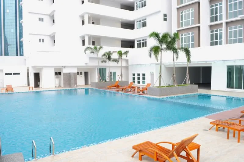 Exterior type: high-rise condominium; features: infinity pool, pool deck with loungers, palm trees, glass facade, white painted facade, manicured landscaping, outdoor seating area; style: modern.