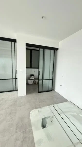 Room features: white painted walls, large glass sliding doors, grey tile flooring, minimalist design, natural light from windows, open layout, visible bathroom area, no visible furniture; style: modern.