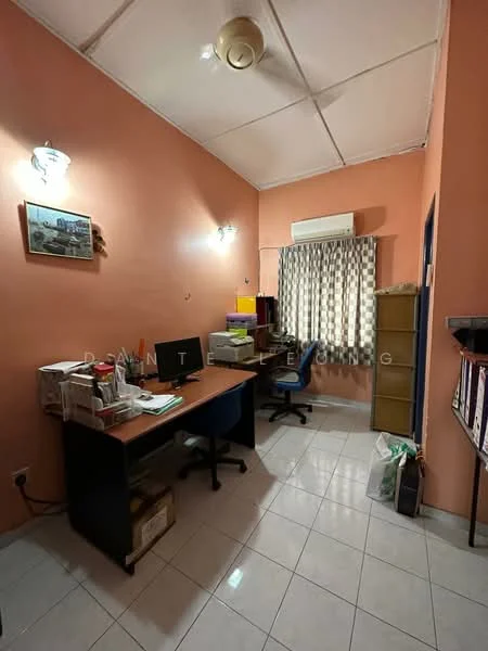 Study features: orange painted walls, white tiled flooring, ceiling fan, window with sheer curtains, wooden desk, blue office chair, filing cabinet, stacked boxes, shelf with books, wall-mounted light fixtures.