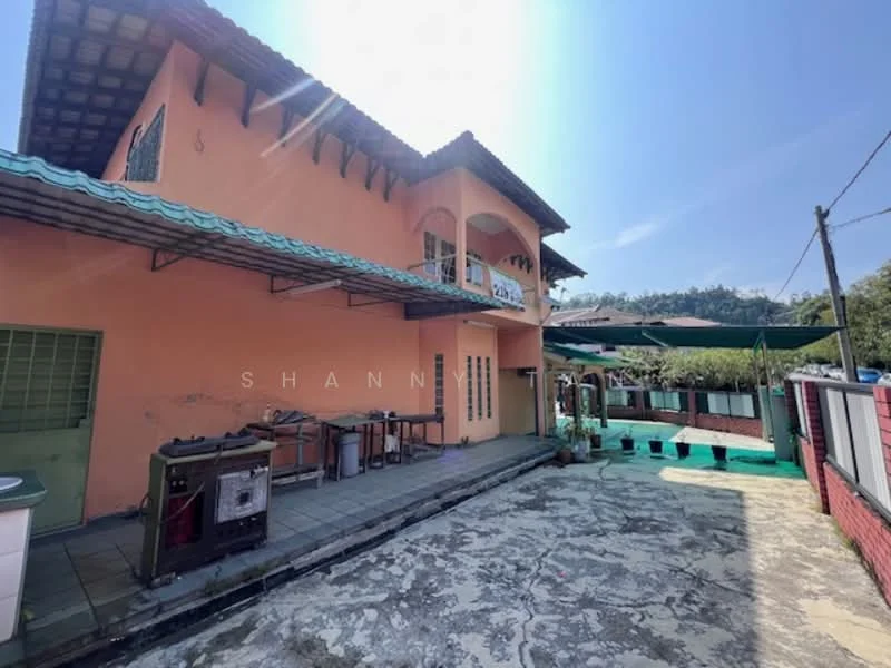 Exterior type: detached bungalow; features: orange painted facade, flat roof with overhang, covered patio area, outdoor dining space with tables, stone-paved flooring, green awning, surrounded by greenery, mountain view in background; style: traditional.