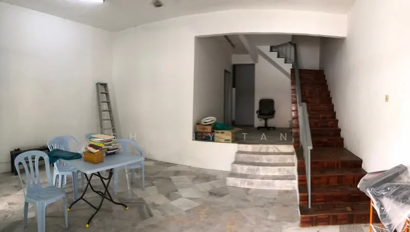 Room features: white painted walls, marble tile flooring, staircase with wooden steps, metal railing, table with blue plastic chairs, stack of books on table, ladder against wall, boxes on floor, office chair in background; style: minimalist.
