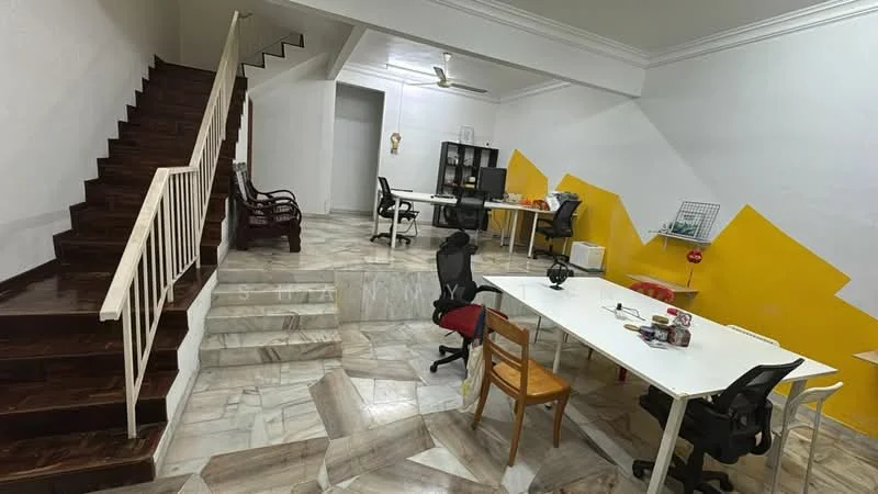 Room features: marble flooring, wooden staircase, white painted walls, ceiling fan, multiple work desks, office chairs, decorative wall with yellow accent, open layout, natural light from windows, shelves, decorative items on desks; style: modern.