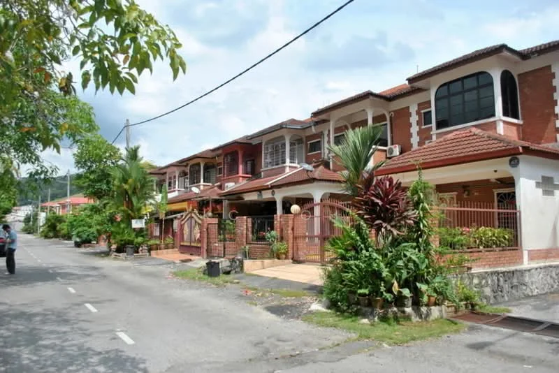 Exterior type: linked terrace house; features: red brick facade, pitched tile roof, manicured lawn, tropical landscaping, palm trees, stone-paved walkway, front porch with railing, visible car porch, decorative plants in pots; style: modern.