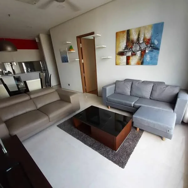 Living features: 3-seater fabric sofa in grey, 2-seater fabric sofa in beige, coffee table with wooden base and black top, area rug with geometric pattern, wall-mounted artwork with abstract design, recessed downlights, ceiling fan, open shelving, light fixture hanging above dining area; style: modern.